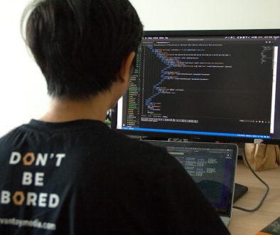 man in black shirt using laptop computer and flat screen monitor developers working, coding teamwork, programming languages