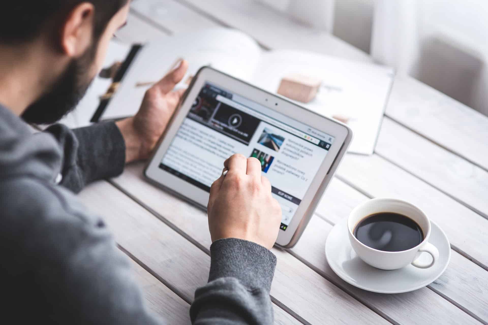 Man using tablet and drinking coffee