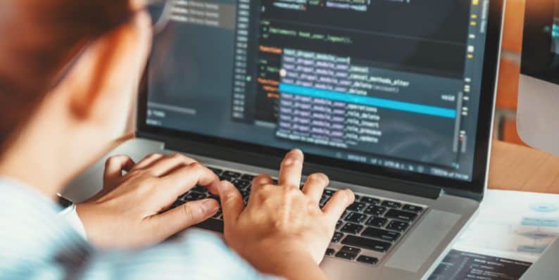 Person typing code on a laptop with backend development tools visible, illustrating backend developer tasks.