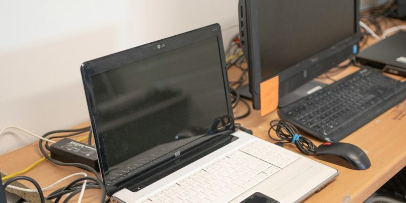 a desk with two laptops and a keyboard on it laptop docking station, tech workspace, minimalist office setup