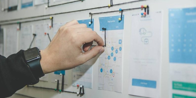 person working on blue and white paper on board canva interface, resume design, creative field
