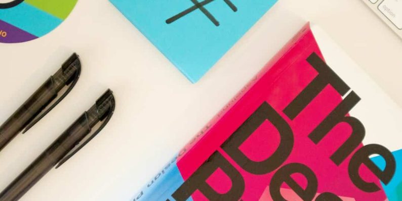 a desk with a keyboard, pen, and a book logo design sketches, branding tools, creative desk
