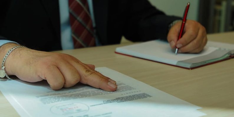 a man in a suit signing a document with a pen property manager, vendor meeting, agreement document