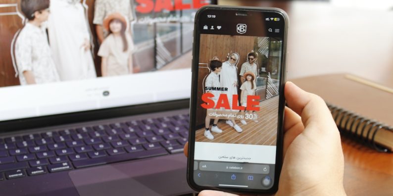 A person holding a cell phone in front of a laptop tiktok ecommerce, smartphone shopping, video marketing