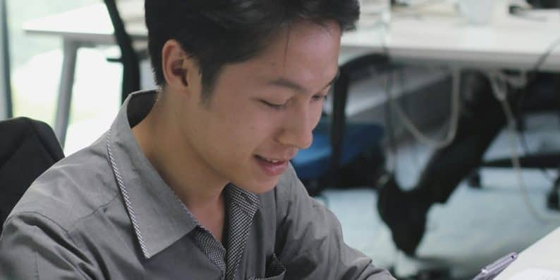 a man sitting at a desk using a cell phone seo agency team, digital marketing strategy, link building tools