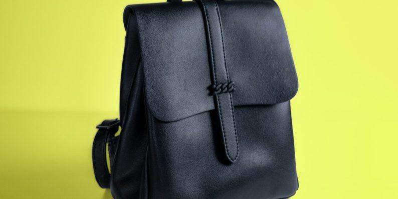 a black leather backpack on a yellow background senreve maestra bag, leather luxury handbag, convertible backpack purse