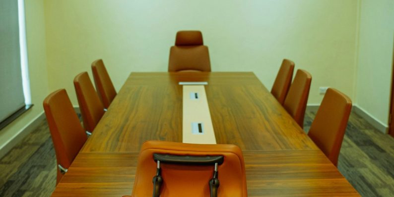 a conference table with a laptop on top of it meeting room, executives, technology tools