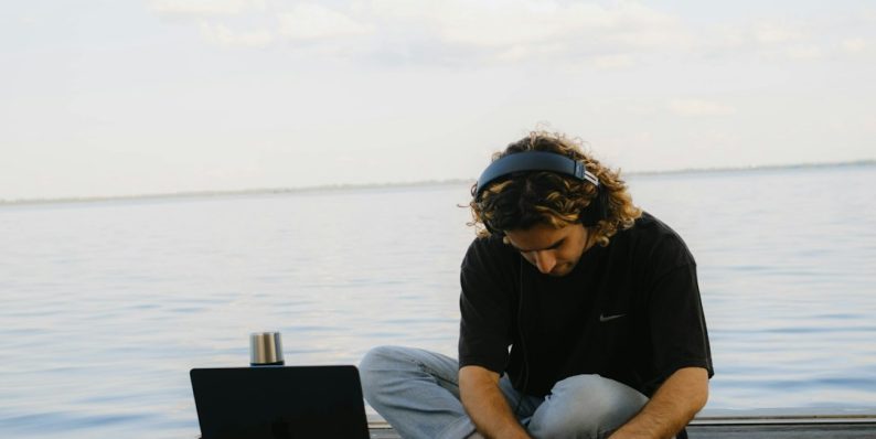 a man sitting on a dock working on a laptop business owner working on laptop, wordpress admin dashboard, cybersecurity lock icon