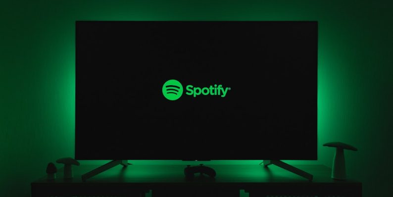 the spotify logo is lit up on a flat screen tv spotify free, music ads, listening limitations