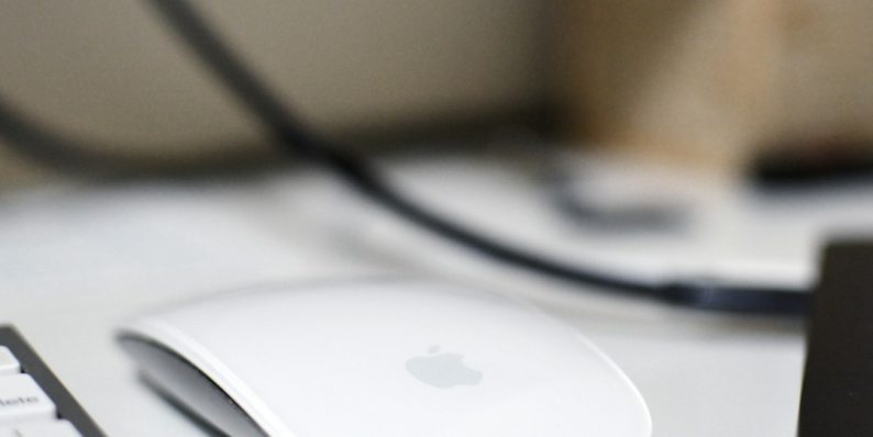 a computer mouse sitting on top of a white desk macbook mouse settings user interface, system preferences