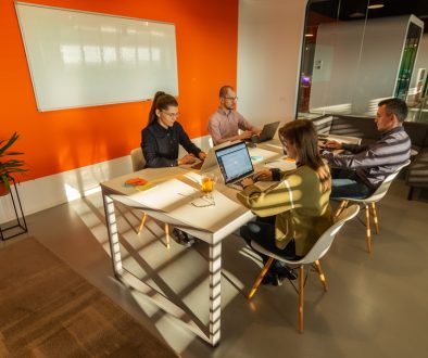 a group of people sitting around a table with laptops remote work, hybrid teams, collaboration tools a group of people sitting around a table with laptops remote work, hybrid teams, collaboration tools