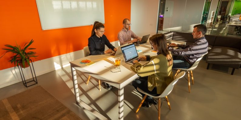 a group of people sitting around a table with laptops remote work, hybrid teams, collaboration tools a group of people sitting around a table with laptops remote work, hybrid teams, collaboration tools