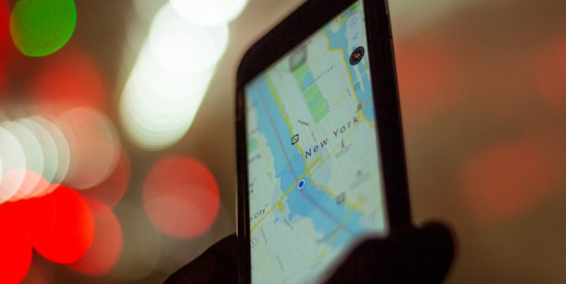 person holding smartphone displaying GPS tracking apps, delivery management, smartphone dashboard