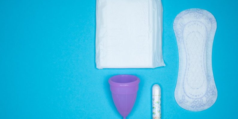 a blue table with a toothbrush, a tube of toothpaste and a sanitary pads packaging, menstrual hygiene, feminine care