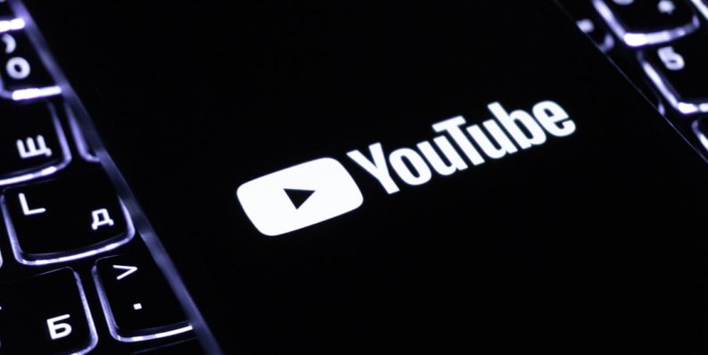 The youtube logo on a smartphone is visible. youtube demonetization, content flagging, community guidelines