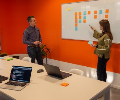 a man and a woman standing in front of a whiteboard startup team meeting, hiring strategy, office culture