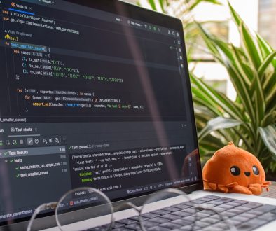 Laptop screen displaying code with a small octopus toy. developers working, coding teamwork, programming languages
