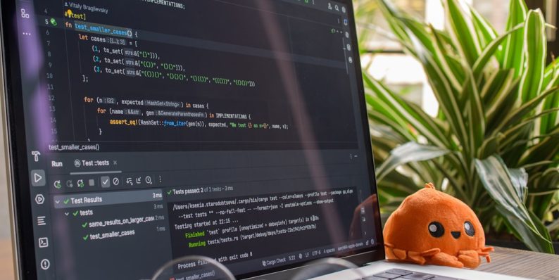 Laptop screen displaying code with a small octopus toy. developers working, coding teamwork, programming languages