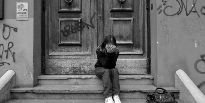 a person sitting on steps outside a building unemployment, school child, financial stress, family home