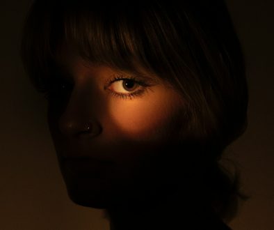 A woman's eye is lit by a warm glow. portrait lighting examples contrast shadows