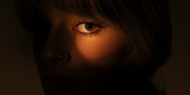 A woman's eye is lit by a warm glow. portrait lighting examples contrast shadows A woman's eye is lit by a warm glow. portrait lighting examples contrast shadows
