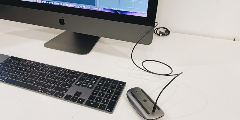 silver imac beside apple magic keyboard and apple magic mouse student laptop writing editing tools