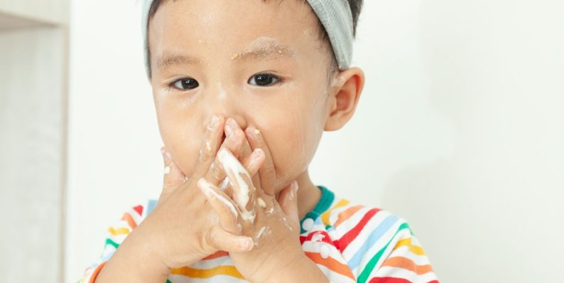 A little girl standing in a kitchen with a messy face child with nasal congestion, sore throat, adenoiditis