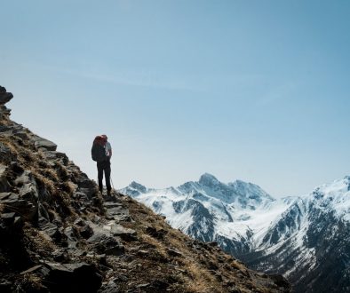 A lone hiker stands on a rocky mountain trail. mountain hiking trail, alpine landscape, backpacker trekking, high altitude scenery