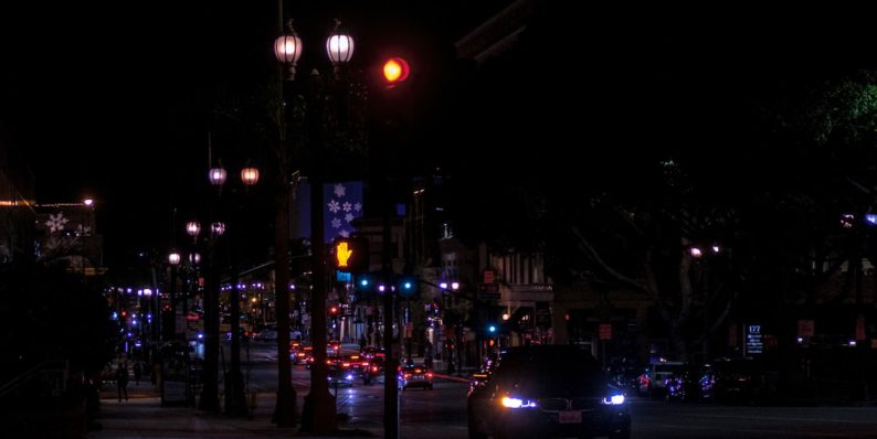 Car driving at night on a city street. smart traffic camera at intersection, night city street, police car lights